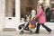 Mother Pushing Stroller By Clothes Shop