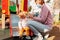 A mother puts a medical mask on her little child sitting on a children's slide. Virus protection in public places