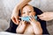 Mother puts a medical protective mask on the face of her young child, the Child is sitting in a feeding chair. Quarantine,