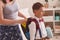 Mother puts a Packed school lunch a plastic box in her son`s backpack at school