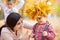 Mother puts yellow fallen leaves on son head. Happy family is in autumn city park. Children and parents. They posing, smiling, pla