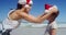 Mother putting santa hat on girl head at beach