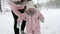 Mother raises baby from the snow. Child in warm jumpsuit learns to walk. Girl walking doing first steps in winter forest