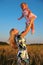 Mother raises child on hands in wheaten field