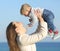 Mother raising her baby son outdoors on the beach