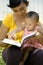Mother reading while babysitting baby