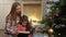 Mother reading book to daughter near xmas tree.