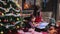 Mother reads a book for her daughter near the Christmas tree.