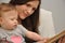 Mother reads a book to a baby daughter