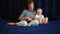 Mother reads a book to a baby sitting on a mattress