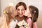 Mother receiving flowers from her cute little daughters at home