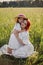 mother with red hair and a hat is sitting in a green field with grass with her daughter of four years sunset