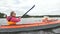 mother rows kayak with little kid against forest and sky