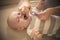 Mother rubs teeth of her little baby boy with gel.