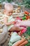 The mother`s hand extends a fresh tomato to a newborn child sitting in a field among vegetables