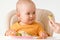 The mother`s hand gives the baby sitting on a feeding chair boiled broccoli. The concept of healthy nutrition for babies