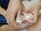 Mother`s hands holding her daughter`s hands teaching her baby to peel fruit, pomelo