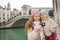 Mother showing photo to daughter in front of Rialto Bridge