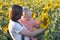 Mother shows her little daughter a large sunflower flower on the field. Summer outside the city