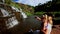 Mother Sits Holds on Knees Little Girl Makes Selfie by Waterfall