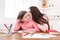 Mother sitting with her daughter kissing her cheek at home