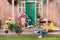 Mother sitting in rocking chair and smiling daughter cultivating plant on porch