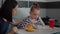 Mother sitting with sick daughter while eating healthy food meal in hospital ward