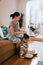 Mother sitting on the sofa braids her daughter`s hair sitting on the floor next to her in the cozy light room