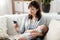 Mother with sleeping baby and smartphone at home