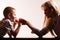 Mother and son arm wrestle sit at table.