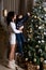 Mother and son decorate a tall fluffy Christmas tree