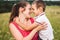 Mother and son hugging in field. Happy mother embracing her son in park. Mother hugging her child. Motherhood. Young mother cuddle