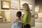 Mother and son looking at paintings in halls of museum