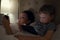 Mother with son looks in their electronic devices lying in bed