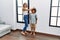 Mother and son measuring child height drawing mark on wall at home