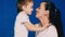 Mother and son play laugh and kiss on a blue background