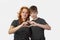 Mother and son show heart by fingers on gray