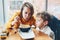 mother and son, sitting in restaurant cafe at table, feeding eating pasta spaghetti