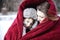 Mother and son snuggling under blanket outside in the snow