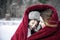 Mother and son snuggling under blanket outside in the snow