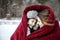 Mother and son snuggling under blanket outside in the snow