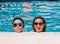 Mother and son with sunglasses are leaning on the edge of the pool on a sunny summer day