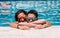 Mother and son with sunglasses are leaning on the edge of the pool on a sunny summer day