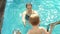 Mother and son swim in the pool, the child climbs into the water on the stairs.