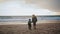 Mother son walking beach holding hands rear view. Carefree family resting sunset