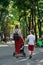 Mother and son walking in park and hold hands. Mom with stroller and an older child. Vertical frame