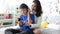 Mother and son wearing headphones using smartphone for listen to music together at home