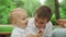 Mother and sons having picnic in park. Toddler taking cherry from mother hand