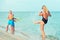 Mother and sons play on the beach with water pistols. Summer time