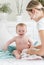 Mother soothing her crying baby boy sitting on bed